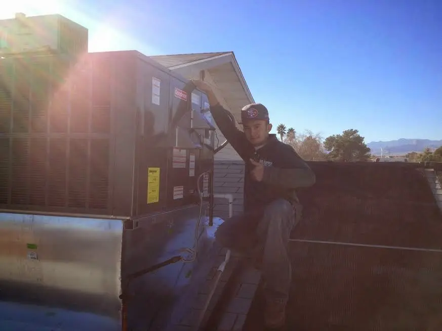 HVAC technician performing Air Duct Cleaning on a rooftop unit in Macclenny
